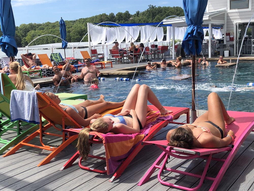 Three friends relaxing in colorful loungers beside the pool